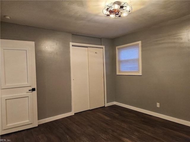 unfurnished bedroom with dark hardwood / wood-style flooring and a closet