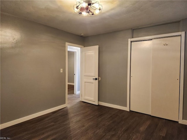 unfurnished bedroom with dark wood-type flooring and a closet