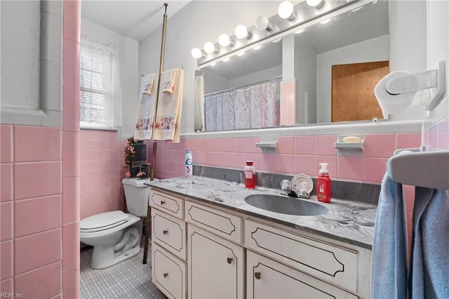 bathroom with tile patterned floors, vanity, toilet, and tile walls