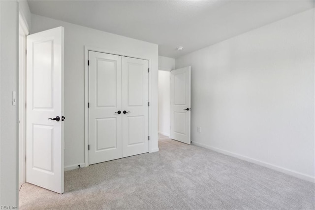 unfurnished bedroom featuring light carpet and a closet