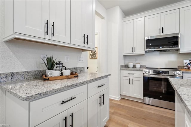 kitchen featuring light hardwood / wood-style flooring, light stone counters, stainless steel appliances, and white cabinetry