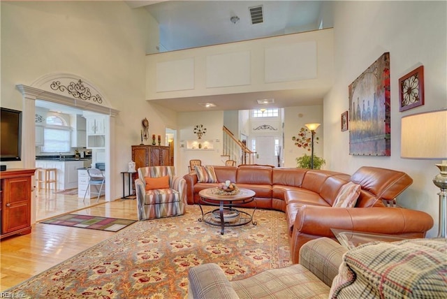 living room with light wood-type flooring and a towering ceiling