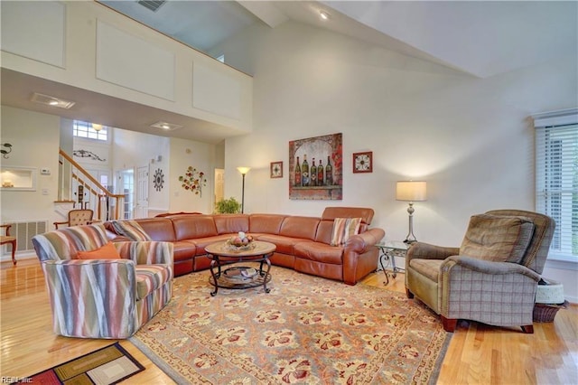 living room featuring high vaulted ceiling and light hardwood / wood-style floors