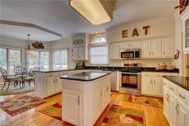 kitchen featuring appliances with stainless steel finishes, white cabinets, pendant lighting, light hardwood / wood-style flooring, and a center island