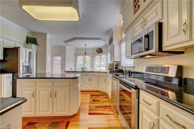 kitchen featuring decorative light fixtures, stainless steel appliances, sink, ornamental molding, and light hardwood / wood-style flooring