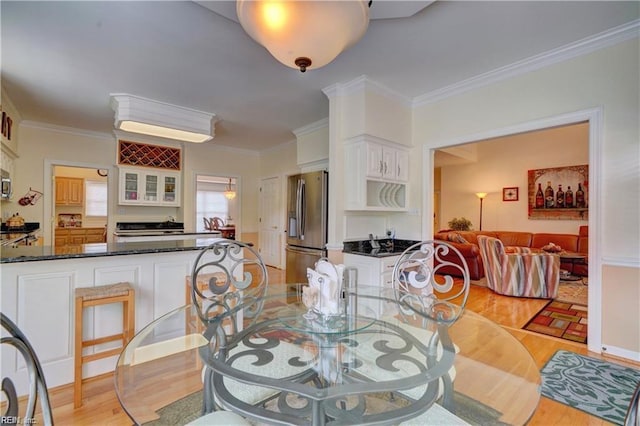 dining area with light hardwood / wood-style flooring and ornamental molding