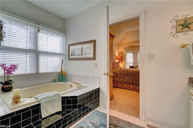 bathroom with tiled tub, tile patterned floors, vanity, and vaulted ceiling