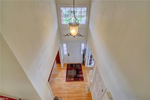 foyer entrance featuring a high ceiling, a chandelier, and light hardwood / wood-style flooring