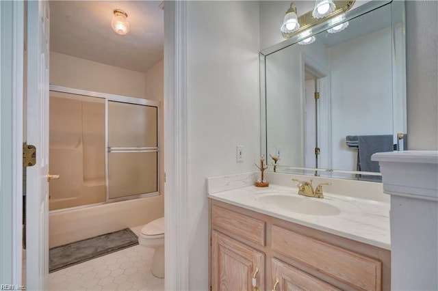 full bathroom featuring combined bath / shower with glass door, vanity, tile patterned floors, and toilet