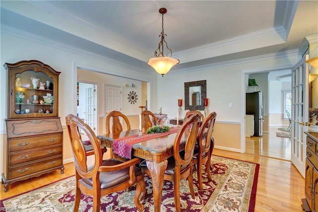 dining space with ornamental molding and light hardwood / wood-style flooring