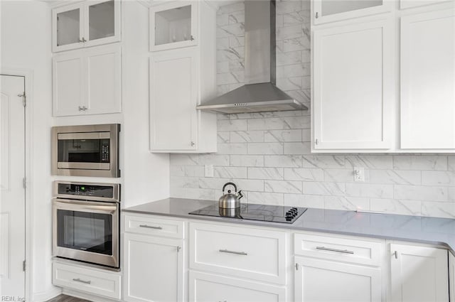 kitchen featuring white cabinetry, wall chimney exhaust hood, and appliances with stainless steel finishes