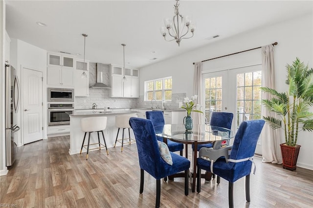 dining room with french doors, sink, a notable chandelier, and light hardwood / wood-style flooring