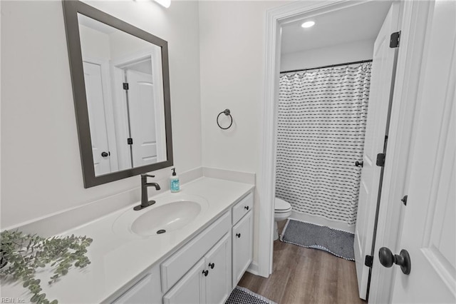 bathroom with toilet, a shower with shower curtain, hardwood / wood-style flooring, and vanity