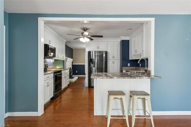 kitchen with white cabinets, stainless steel appliances, sink, kitchen peninsula, and stone counters