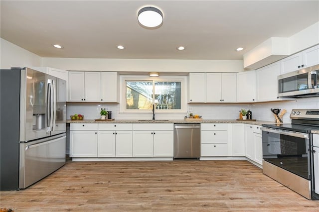 kitchen featuring light wood-type flooring, appliances with stainless steel finishes, white cabinets, and sink