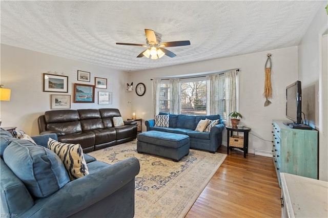 living room with ceiling fan, a textured ceiling, and light hardwood / wood-style floors