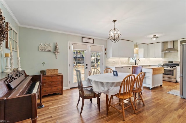 dining area with french doors, an inviting chandelier, ornamental molding, and light hardwood / wood-style flooring