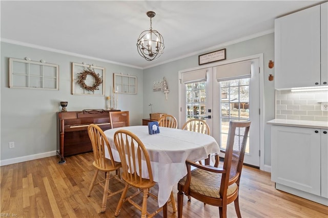 dining space with a chandelier, crown molding, light hardwood / wood-style floors, and french doors