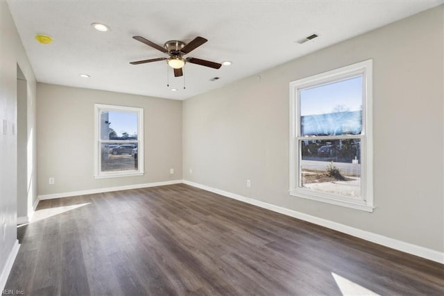 empty room with ceiling fan, a wealth of natural light, and dark hardwood / wood-style flooring