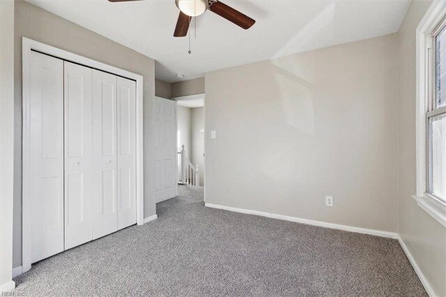 unfurnished bedroom featuring ceiling fan, light colored carpet, and a closet