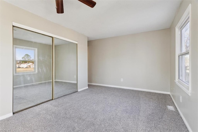 unfurnished bedroom with a closet, carpet, multiple windows, and ceiling fan