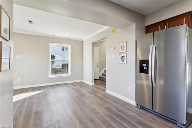 kitchen featuring stainless steel refrigerator with ice dispenser, crown molding, and light hardwood / wood-style floors