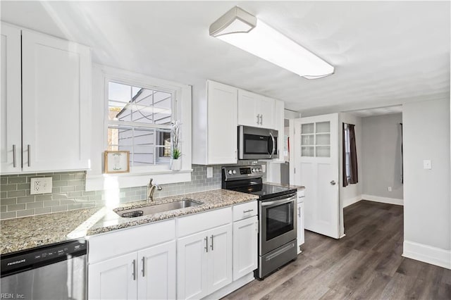 kitchen featuring sink, appliances with stainless steel finishes, white cabinets, light stone countertops, and backsplash