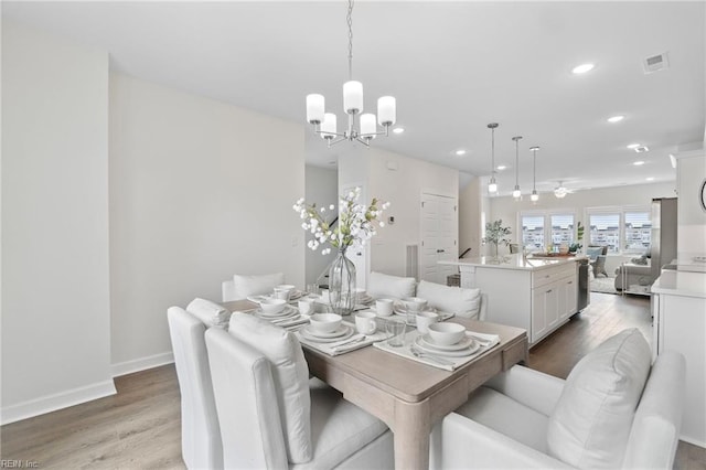 dining room with ceiling fan with notable chandelier and hardwood / wood-style flooring