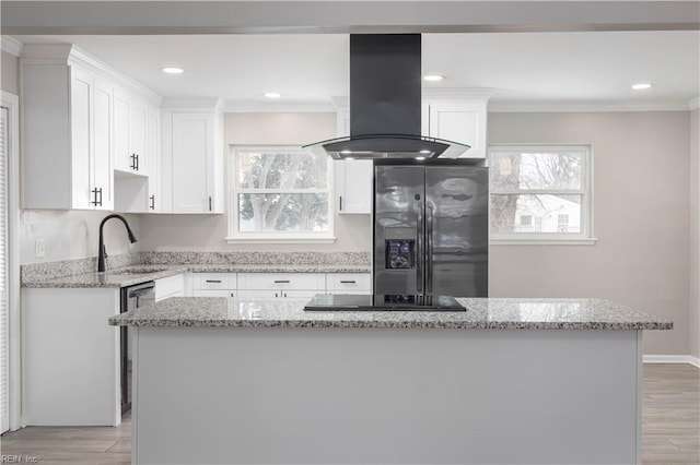 kitchen featuring white cabinets, appliances with stainless steel finishes, island exhaust hood, and a kitchen island