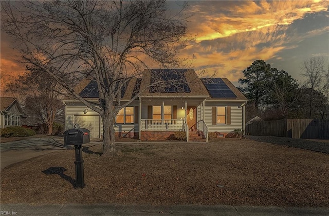 view of front of property featuring a garage, a porch, and solar panels