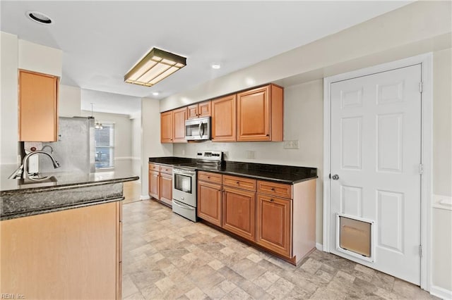 kitchen featuring appliances with stainless steel finishes, dark stone countertops, and sink