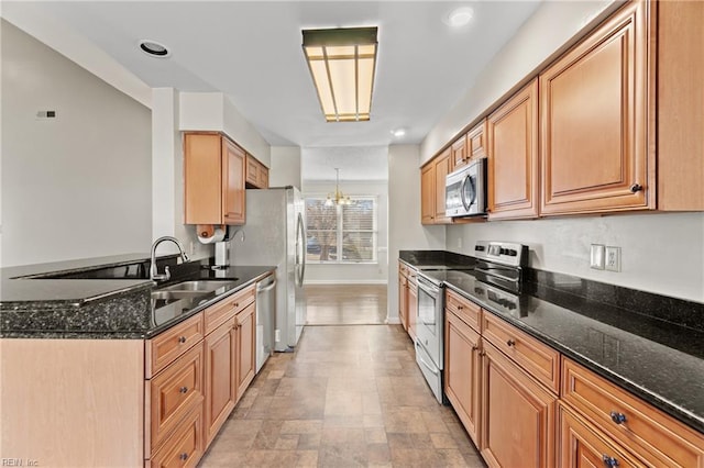 kitchen with sink, a notable chandelier, dark stone countertops, and stainless steel appliances