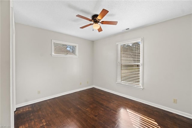 empty room with ceiling fan, dark wood-type flooring, and a textured ceiling