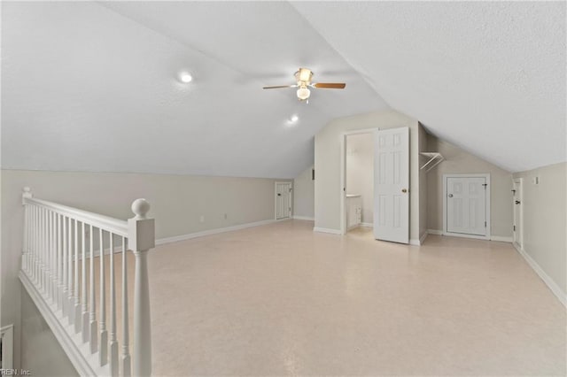 additional living space with vaulted ceiling, ceiling fan, and a textured ceiling