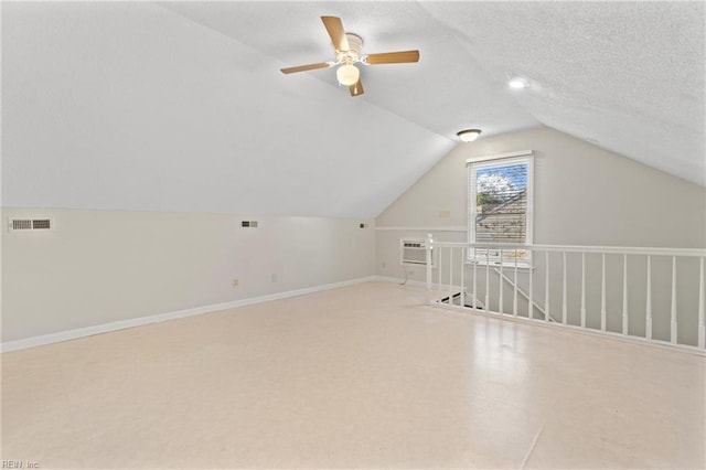 additional living space with a textured ceiling, lofted ceiling, and a wall mounted AC