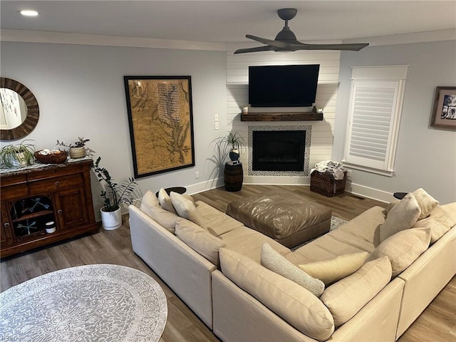 living room with hardwood / wood-style flooring, a fireplace, ornamental molding, and ceiling fan