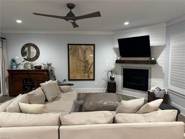 living room with ceiling fan, ornamental molding, hardwood / wood-style floors, and a tile fireplace