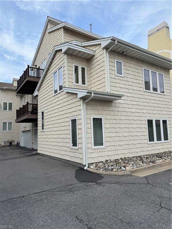 view of side of home with a garage and a balcony