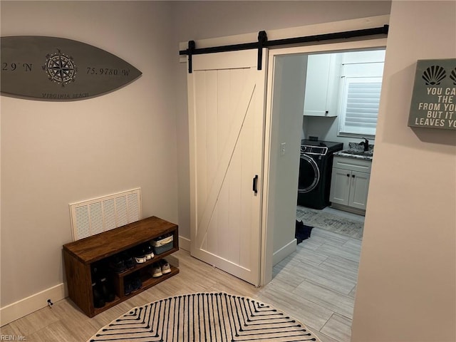 hall featuring washer / clothes dryer, a barn door, and sink