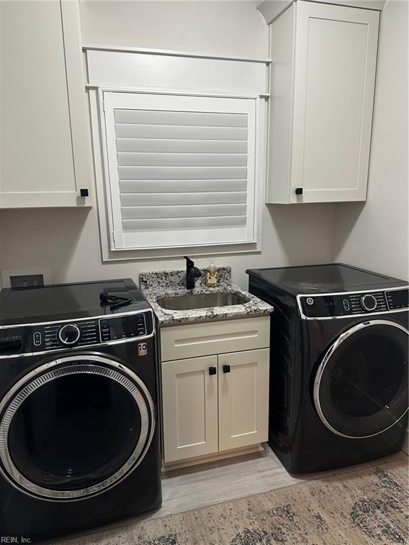 washroom featuring washer / clothes dryer, cabinets, sink, and light wood-type flooring