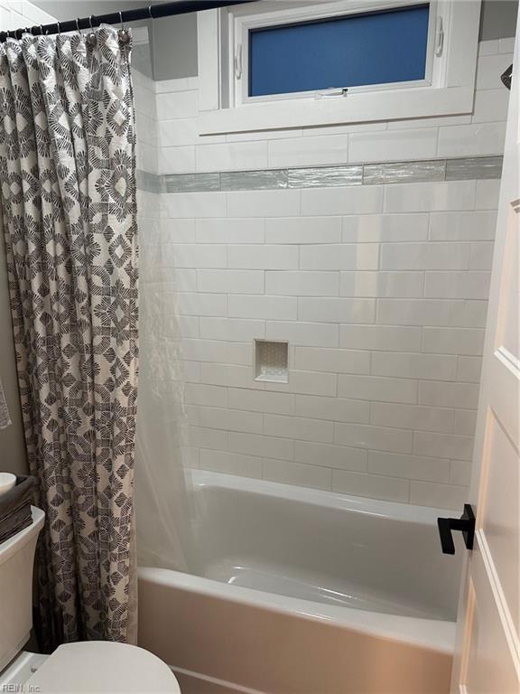 bathroom with shower / bath combination with curtain and toilet