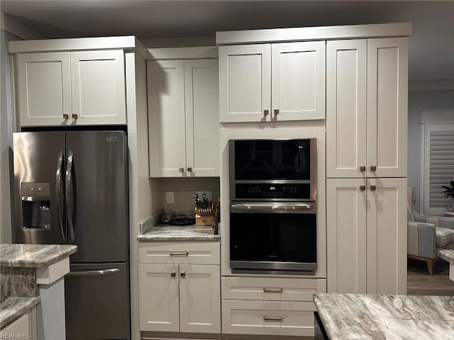 kitchen featuring stainless steel appliances, white cabinets, and light stone counters