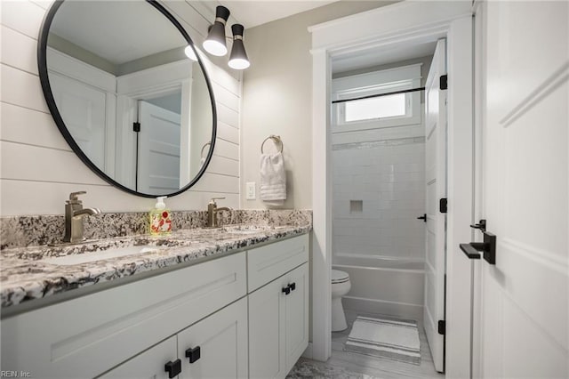 full bathroom featuring vanity, tiled shower / bath combo, and toilet