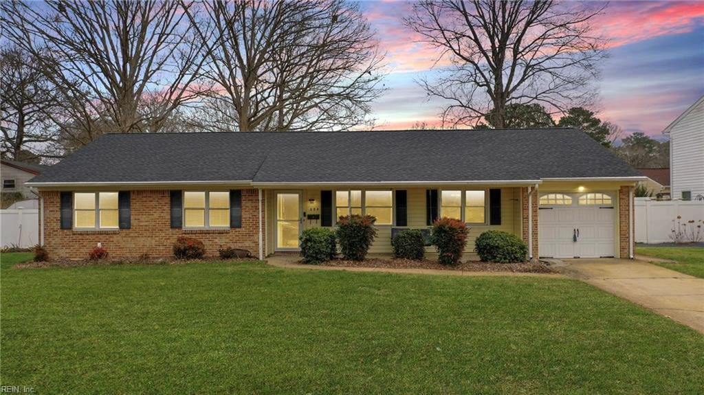 single story home featuring a garage and a yard