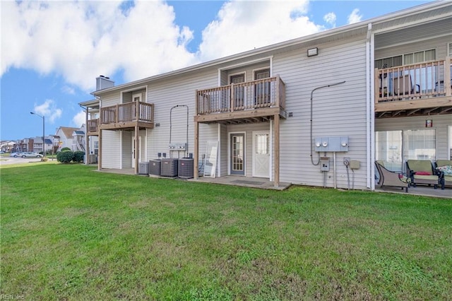 back of property featuring central AC unit and a lawn