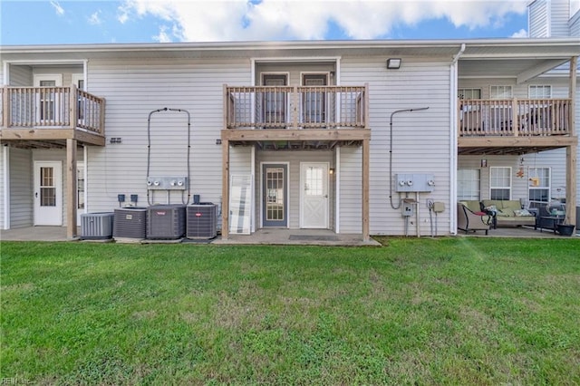 rear view of property featuring a balcony, a yard, and central AC unit