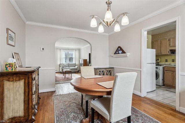 dining room featuring light hardwood / wood-style floors, a notable chandelier, ornamental molding, and washer / clothes dryer