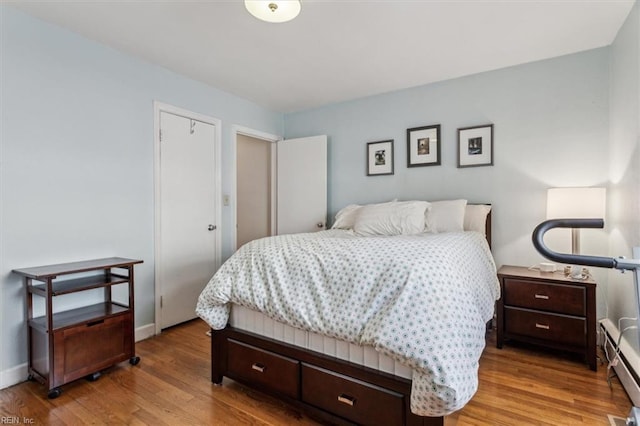 bedroom with light wood-type flooring and a baseboard heating unit