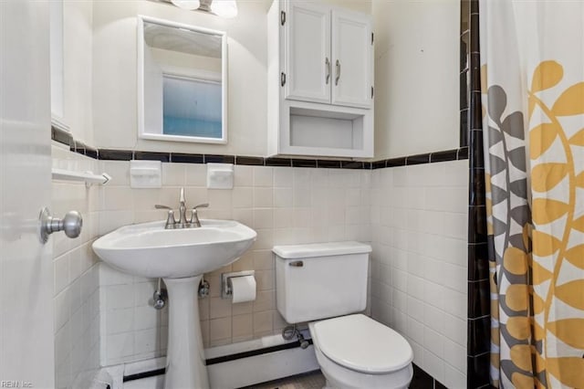 bathroom featuring curtained shower, toilet, and tile walls