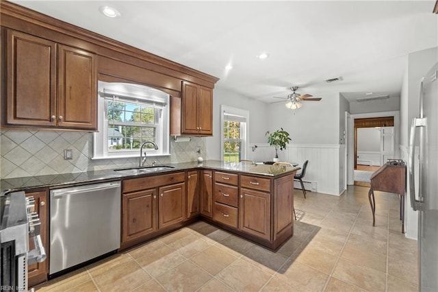 kitchen featuring a baseboard heating unit, dark stone countertops, kitchen peninsula, sink, and appliances with stainless steel finishes